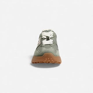 Green sneaker with brown sole on a light gray background