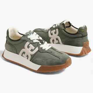 Green sneakers with white laces and brown soles on a white background