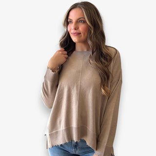 Woman wearing a beige long sleeve top against a white background