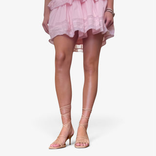 Nude kitten heel sandals with lace-up ankle straps styled with a pink dress, front view