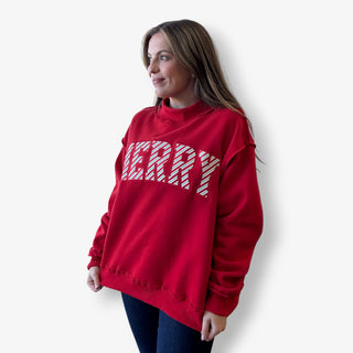 Woman wearing a red sweatshirt with 'MERRY' text on a white background