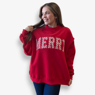 Woman wearing a red sweatshirt with 'MERRY' text on a white background