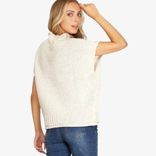Woman wearing ivory mock neck knit sweater top with sleeveless design and relaxed fit