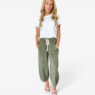 Moss green cotton balloon pants with oversized patch pockets, contrast stitching and rope drawstring waist, front view
