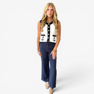 Ivory nautical knit vest with navy contrast trim, gold buttons and anchor pockets styled with navy pants, full-body front view
