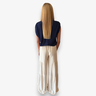Woman modeling a navy ruched shoulder top with ivory tiered wide leg pants, back view showing the gathered shoulder detail.