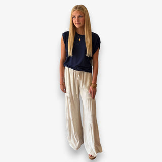 Woman modeling a navy ruched shoulder top with ivory tiered wide leg pants, full front view.
