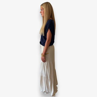 Woman modeling a navy ruched shoulder top with ivory tiered wide leg pants, side view showing the relaxed draped fit.