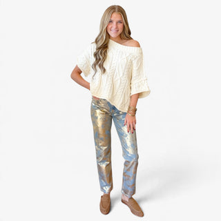 Nerissa metallic straight leg jeans featuring gold foil detailing over blue denim, styled with an ivory cable knit sweater and tan loafers, full front view.