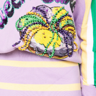 Queen of Sparkles lilac Queen Cake striped Mardi Gras sweater with sequin cake graphic and green and yellow trim.