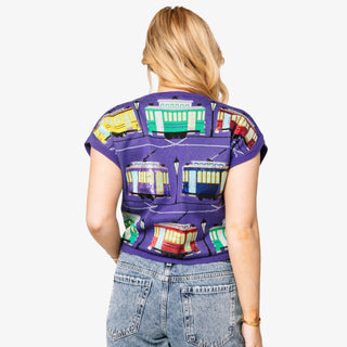 Person wearing a purple shirt with colorful tram pattern on a white background