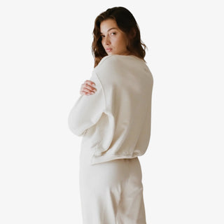 Woman wearing a beige long-sleeve top and pants on a white background