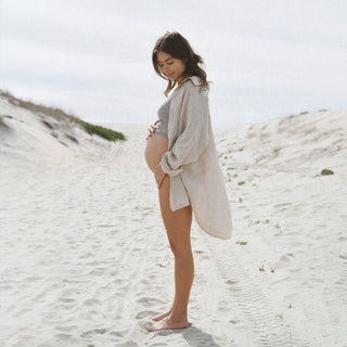 Oatmeal oversized linen shirt with rolled sleeves standing on sand dunes lifestyle view