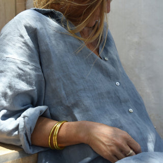 Close up of slate blue oversized linen shirt with mother of pearl buttons and rolled sleeves