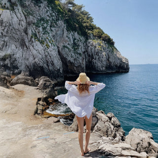 Oversized white linen beach cover up shirt overlooking coastal ocean cliffs back view