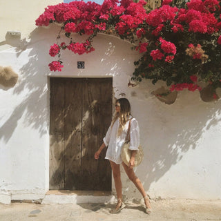 White oversized linen shirt with rolled sleeves walking by pink flowers lifestyle view
