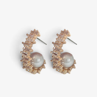 Gold pearl crystal hoop earrings featuring white baguette crystals surrounding a luminous center pearl, 1.25-inch length, angled side view.