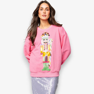 Woman wearing a pink sweatshirt with a colorful nutcracker design on a white background