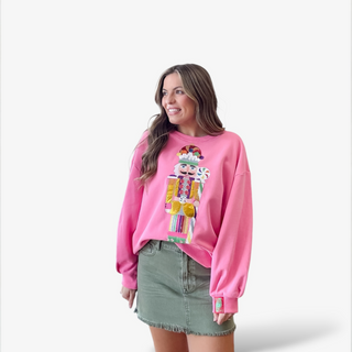Woman wearing a pink sweatshirt with a colorful nutcracker design on a white background
