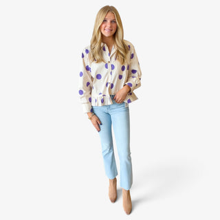 Purple polka dot ruffle hem shirt styled with light wash jeans and ankle boots, full-length view