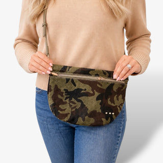 Pretty Simple Westlyn Hide Bum Bag in camo with adjustable crossbody strap and front zipper pocket, shown worn by a woman in a lifestyle view.