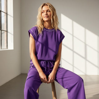 Purple scuba lounge set with relaxed sleeveless top and drawstring pants for polished casual wear, seated view