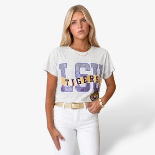Queen of Sparkles LSU Metallic Banner Tee in light gray with purple and gold sequin lettering, tiger patch, white jeans and gold belt, front view