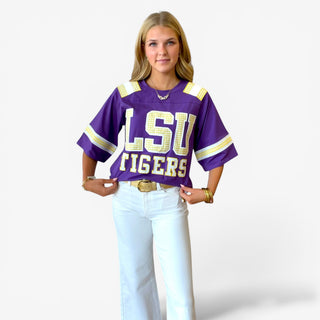 Queen of Sparkles LSU oversized jersey in purple with gold and white details, full front view styled with white jeans