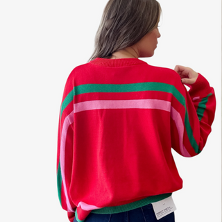 Red sweater with green and pink stripes worn by a person on a white background