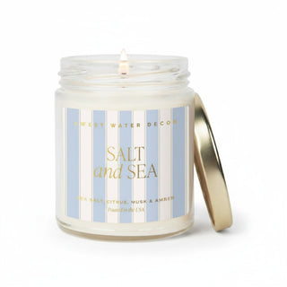 Sea salt candle in blue striped glass jar with gold lid on white background front view