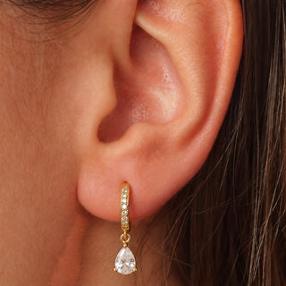 Saône 18K gold non-tarnish CZ huggie earring with teardrop crystal shown on ear, model view