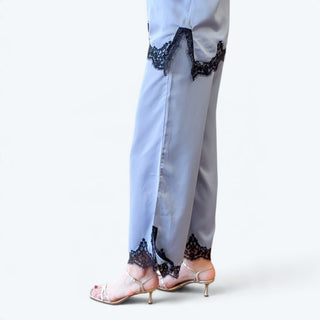 Side close-up of light blue satin wide leg pants featuring black lace trimmed hems and cropped length, paired with strappy heels.