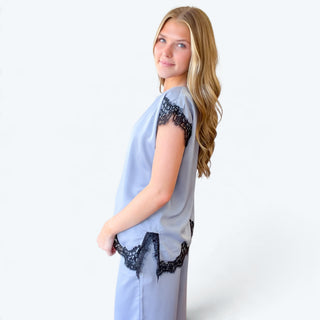 Side view of light blue satin lace trim pant set showing relaxed top, black lace sleeve detailing, and lace-trimmed side slit.
