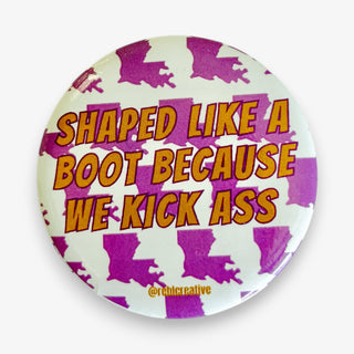 Shaped Like a Boot Because We Kick Ass 2.25-inch game day button with gold lettering and purple Louisiana silhouettes on a white background.
