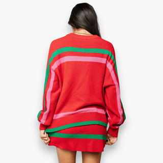 Person wearing a red sweater with green and pink stripes on a white background