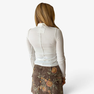 White Sloane seam turtleneck top featuring exposed contrast seam details down the back and sleeves, back view.