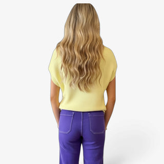 Soft yellow knit top with relaxed silhouette and cap sleeves styled with purple pants, back view.