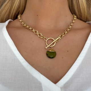 Spearmint pendant necklace with textured gold chain, toggle closure and round faceted green pendant, shown worn in a close-up front view