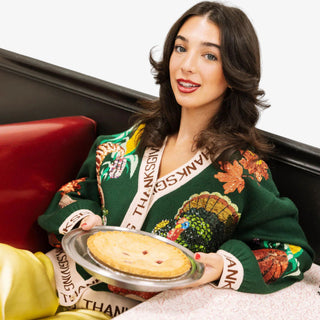 Woman wearing a Thanksgiving-themed sweater holding a pie