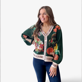 Woman wearing a festive green sweater with Thanksgiving-themed designs on a white background