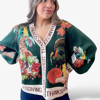 Person wearing a festive green sweater with Thanksgiving-themed designs on a white background