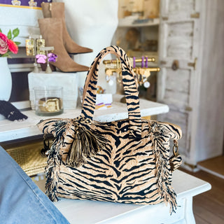 Tiger print duffle bag in tan and black with fringe trim and tassel detail, front view for weekend travel and game day