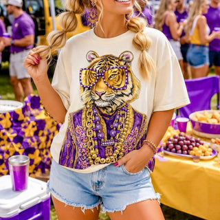Cream tiger rhinestone tee with purple sunglasses and gold jewelry styled with denim shorts for LSU game day, front view.