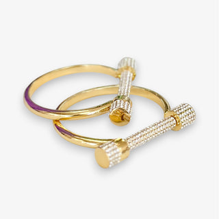 Gold bangle with cubic zirconias and cylindrical ends on a white background