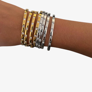 Gold and silver crystal bangle bracelets stacked on wrist with clear rhinestone details