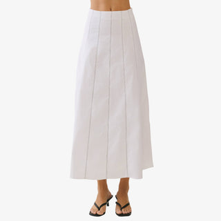 Ivory high waisted maxi skirt with vertical contrast stitching and A-line silhouette styled with black heeled sandals