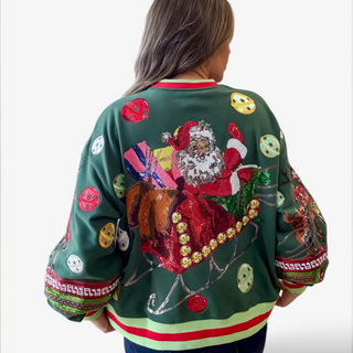 Person wearing a festive green sweater with Santa Claus and Christmas-themed designs.