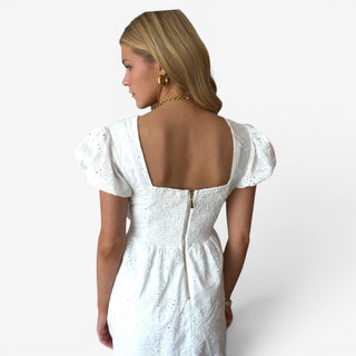 White eyelet mini dress with smocked back and exposed zipper shown in a close-up back view