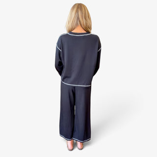 Black women's matching pant set with a relaxed crewneck top, light contrast stitching and cropped wide leg pants, full back view.